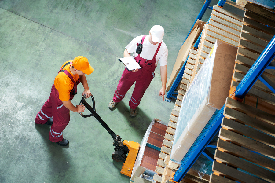 Warehouse supervisor instructing worker on use of fork pallet stacker equipment